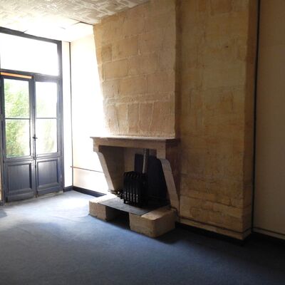 Intérieur du bâtiment rénové. Cheminée et murs en pierres apparentes.