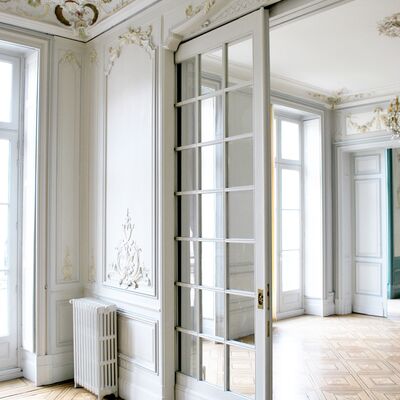 Pièce lumineuse. Verrière et sol en losange en bois. Moulures blanches et or sur les murs et plafond.