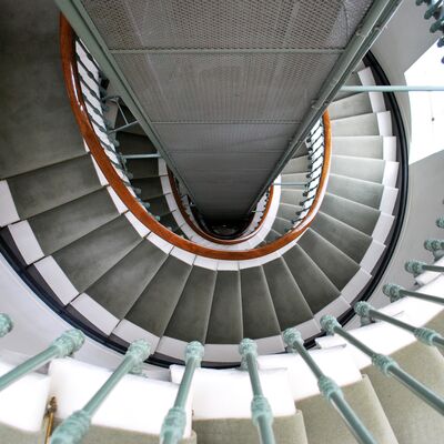 Cage d'escalier grise. Rampe en bois et vert d'eau.