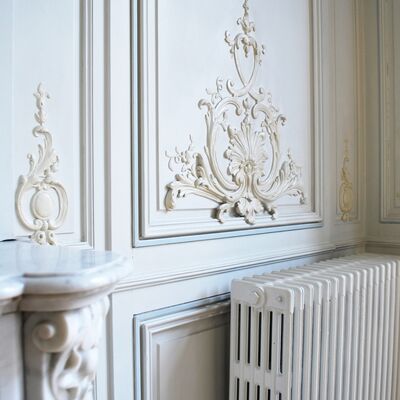 Radiateur ancien avec moulures sur les murs.