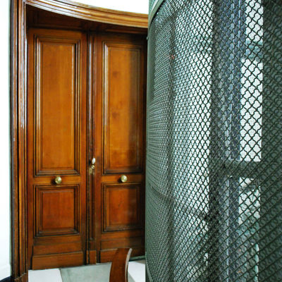 Couloir avec porte en bois massive et cage d'escalier grillagée.