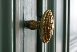 Poignée de porte dorée avec moulures. Porte vert sombre.