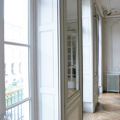 Grande fenêtre donnant sur rue et bâtiment bordelais. Parquet ancien. Pièce lumineuse.